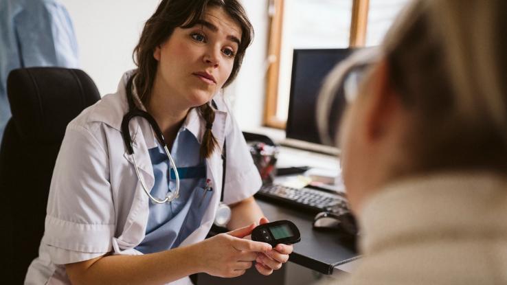 A doctor shows someone with diabetes how to check their blood sugar.